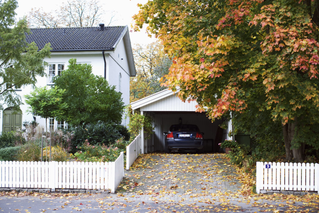 Garage med parkerad bil vid vit villa.